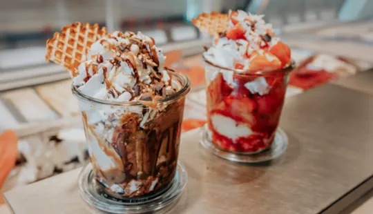 Zwei leckere Eisbecher, einer mit Schokolade und Waffel, der andere mit Erdbeeren, auf dem Tresen eines Cafés in Zinnowitz